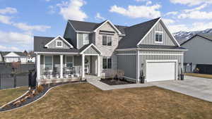 View of front of house with board and batten siding, a porch, a standing seam roof, concrete driveway, and stone siding