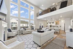Living area featuring light wood-style flooring, a high ceiling, recessed lighting, and a fireplace
