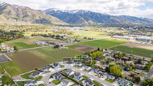 Aerial view of sparsely populated area featuring nearby suburban area, mountains, and extensive farmland