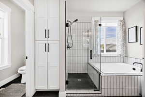 Bathroom with a bath, a shower stall, dark tile patterned flooring, and a closet