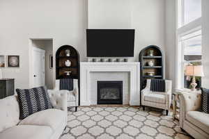 Living area featuring built in shelves, a high ceiling, and a fireplace