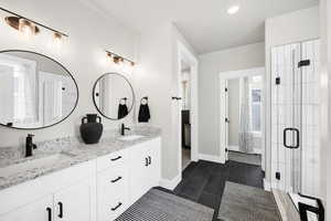 Full bath with double vanity, a stall shower, and dark tile patterned flooring