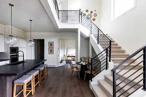 Kitchen featuring a high ceiling, dark countertops, decorative light fixtures, dark wood-type flooring, and a kitchen breakfast bar