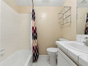 Full bath featuring vanity, shower / bath combo with shower curtain, and light tile patterned floors
