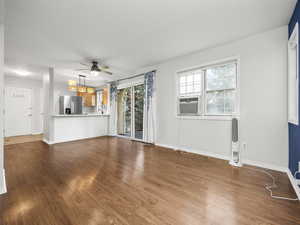 Unfurnished living room featuring dark wood finished floors, ceiling fan, and cooling unit