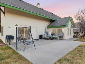 Back of property with roof with shingles, stucco siding, and a patio area