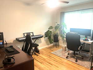 Office with light wood finished floors and a ceiling fan