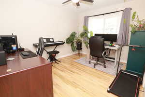 Office with light wood-style flooring, ceiling fan, and a baseboard heating unit