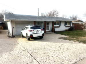 Ranch-style home featuring a shingled roof, brick siding, an attached garage, and driveway