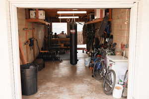 Garage featuring white refrigerator and concrete block wall