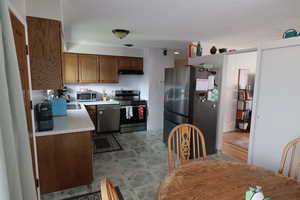 Kitchen featuring light countertops, stainless steel appliances, wood finish cabinets, a textured ceiling, and extractor fan