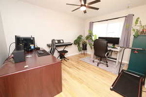 Office area with light wood-style flooring and ceiling fan