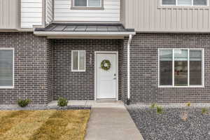 Entrance to property with brick siding and a lawn
