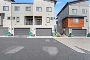 View of front of house with a garage, stucco siding, and a balcony