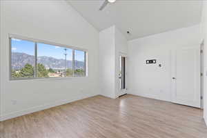 Spare room featuring lofted ceiling, light wood-type flooring, a mountain view, and ceiling fan