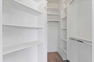 Walk in closet with dark wood-style floors