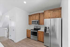 Kitchen featuring stainless steel appliances, light countertops, light wood-style floors, and wood finish cabinets
