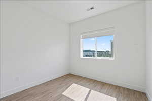 Unfurnished room featuring light wood finished floors and baseboards