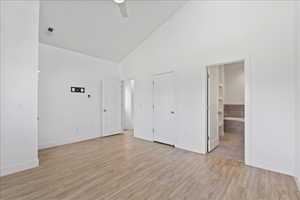 Unfurnished bedroom with vaulted ceiling, light wood-style floors, a ceiling fan, and connected bathroom