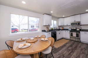 Kitchen featuring white cabinetry, stainless steel appliances, recessed lighting, dark wood-style flooring, and dark stone counters