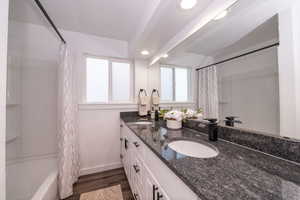 Bathroom with shower / bath combination with curtain, recessed lighting, plenty of natural light, double vanity, and dark wood finished floors
