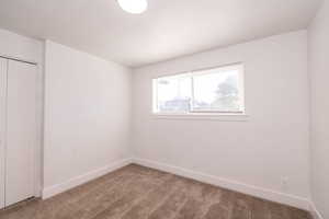 Carpeted spare room featuring baseboards