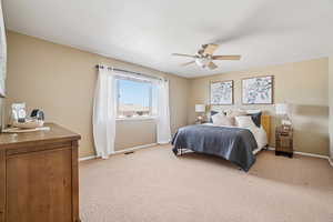 Carpeted bedroom with ceiling fan and baseboards