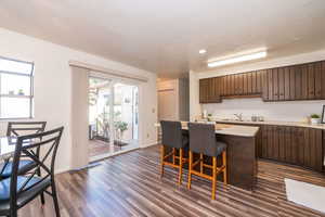 Kitchen with light countertops, a breakfast bar area, dark wood finish cabinetry, a kitchen island, and backsplash
