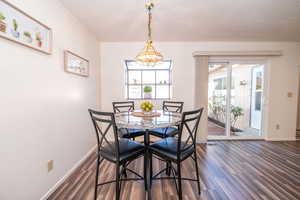 Dining area with dark wood-type flooring and suspended lighting