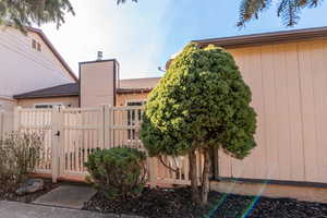 View of side of home featuring a gate and a chimney