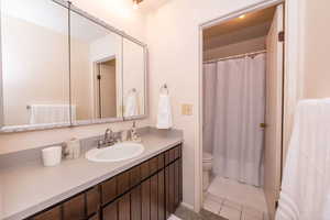 Primary full bath with a shower with shower curtain, vanity, and new light tile patterned flooring