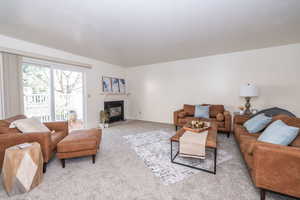 Living area featuring a fireplace with flush hearth and carpet