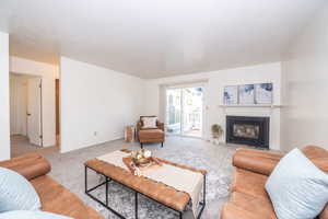 Living room with light colored carpet and a fireplace with flush hearth. Walk out to rear patio.