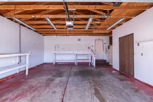 Garage featuring a garage door opener and freestanding refrigerator Storage on side.