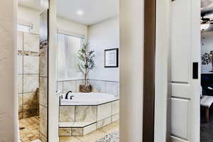 Primary bath with soaker tub, tiled walk-in shower, and frosted glass window.