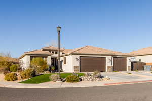 View of facade of home on corner lot featuring three car garage and gates on both sides of property.