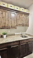Laundry room with granite countertop, sink, and hardwood cabinetry.