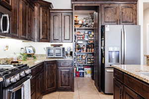Kitchen with hardwood cabinetry, granite countertops, and large hidden pantry.
