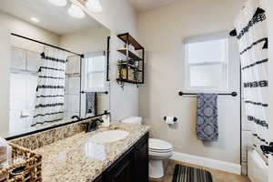 Full bathroom featuring vanity, shower / bath combo with plenty of natural light, and light tile flooring.