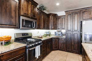 Kitchen with hardwood cabinetry, granite countertops, and large hidden pantry.
