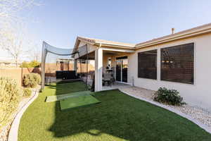 Fenced backyard featuring a covered patio, a hot tub, fully landscaped yard with turf.