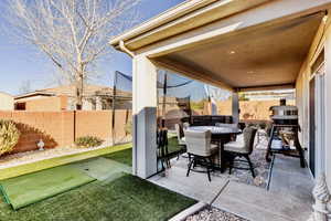Fenced backyard featuring a patio, outdoor dining area, and a putting area