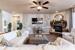 Carpeted living area featuring a ceiling fan, a fireplace, a muraled wall, and recessed lighting.