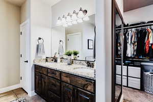 Primary bathroom with a walk in closet, and granite double vanity.