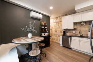 Apt. #2 Kitchen featuring white cabinets, quartz countertops, stainless steel appliances, wood-style floors, mini-split wall unit, and recessed lighting