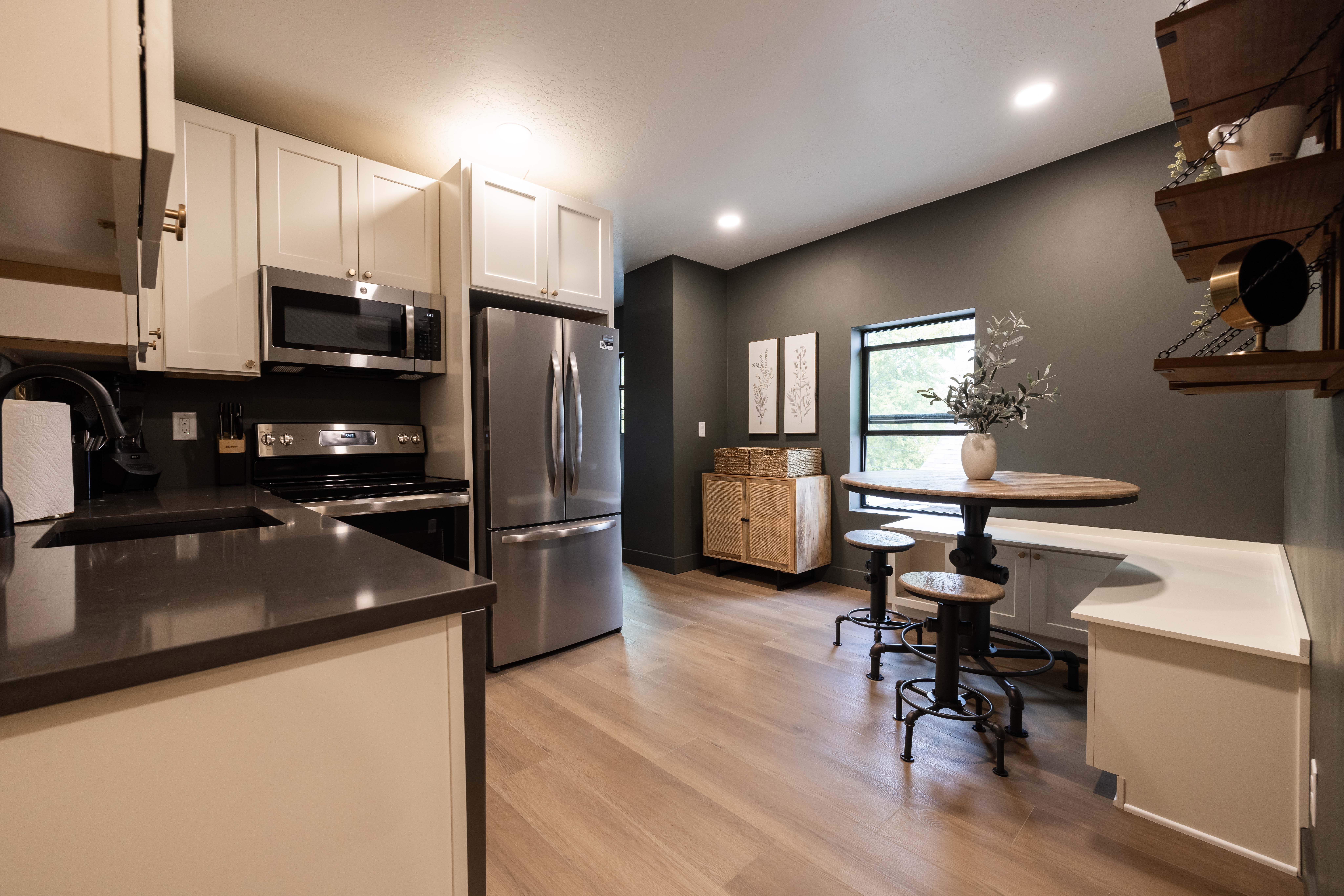 Apt. #4 Kitchen featuring stainless steel appliances, quartz countertops, white cabinets, wood-style flooring.