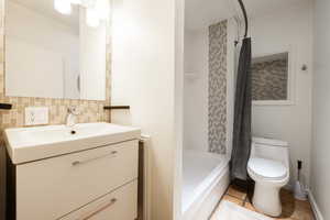 Apt. #3 Full bath with vanity, shower / tub combo, tile patterned flooring, and backsplash