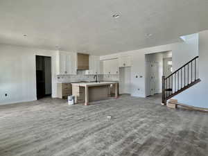 Kitchen with a kitchen bar, an island with sink, tasteful backsplash, light countertops, and wood finished floors
