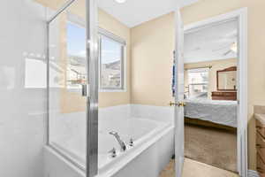Ensuite bathroom with a bath, light carpet, vanity, light tile patterned floors, and an enclosed shower