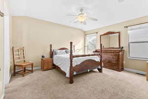 Bedroom with vaulted ceiling, light carpet, and ceiling fan